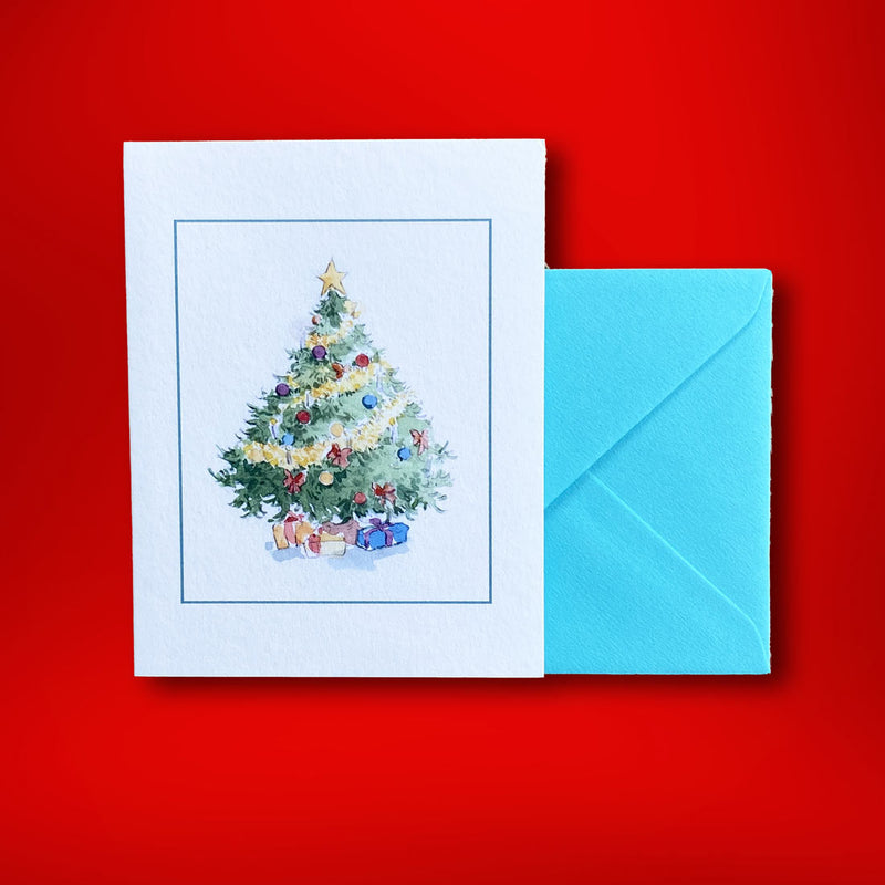 A traditionally decorated tree in a green frame on the face of a folded portrait card with a turquoise blue envelope.